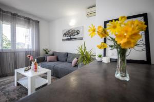 - un salon avec un canapé et une table ornée de fleurs jaunes dans l'établissement Avocado Apartment, à Dubrovnik