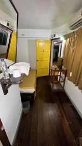Habitación pequeña con cama y puerta amarilla en Relax Guest House, en Patong Beach