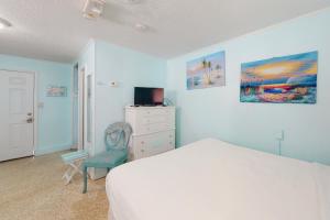 1 dormitorio con cama, silla y vestidor en O'Grady's Little Villa en Panama City Beach
