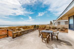 un patio con mesa y sillas y la playa en O'Grady's Little Villa en Panama City Beach
