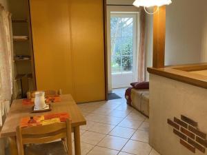 a living room with a table and a kitchen with a window at Charmant gîte rénové avec terrasse privative, jardin et parking - Animaux acceptés - FR-1-489-10 in Neuvy