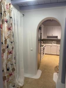 a kitchen with an archway into a kitchen with white cabinets at Aphrodite sunshine suite in Mýkonos City