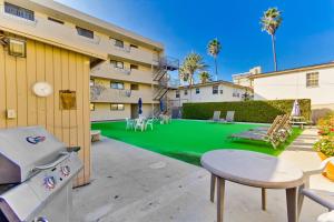 a backyard with a green lawn with a table and a grill at Pool View Condo in San Diego
