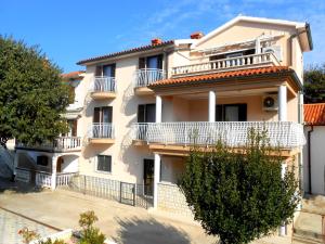 a large white building with balconies and a tree at Villa Luma Apartments in Labin