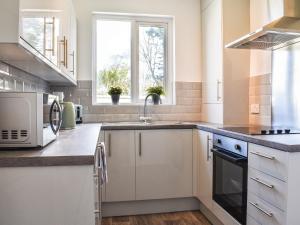 a kitchen with white cabinets and a sink and a window at Mere House in Morecambe