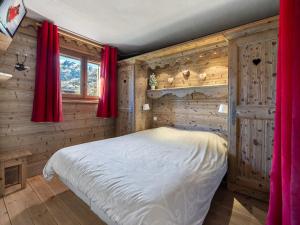 Les Allues的住宿－Appartement Méribel, 3 pièces, 5 personnes - FR-1-566-17，一间卧室设有木墙,另一张床设有红色窗帘