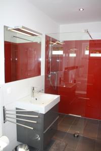 un bagno rosso con lavandino e doccia di Ferienhaus Buhne V a Graal-Müritz