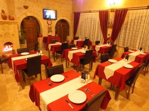 a restaurant with red tables and chairs and a fireplace at Dilek Tepesi Cave Hotel in Ayvalı