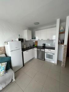 a kitchen with white appliances and a couch in it at Sun Beach 89 in Caleta De Fuste