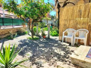 un patio con 2 sedie bianche e un albero di Lemon Casa con giardino a Monterotondo