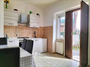 una cucina con armadi bianchi, finestra e lavandino di Lemon Casa con giardino a Monterotondo
