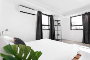 - une chambre avec un lit blanc et 2 fenêtres dans l'établissement Heart of Tel Aviv, Duplex Apartment 12, à Tel Aviv