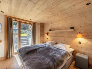 ein Schlafzimmer mit einem großen Bett an einer Holzwand in der Unterkunft Chalet moderne à Méribel avec 5 chambres, sauna et accès rapide aux pistes - FR-1-566-45 in Les Allues