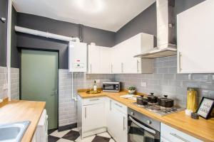 a kitchen with white cabinets and a stove top oven at Ashford House - By Sigma Stays in Etruria