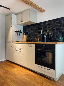 una cocina con armarios blancos y una pared de azulejos negros en Pfalzkind - Ein Stück Heimat im Alltag en Bad Dürkheim