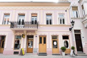 een roze gebouw met gele deuren in een straat bij Key Apartments in Novi Sad