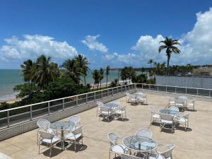 um pátio com mesas e cadeiras e a praia em Bela Hospedagem - #Atlântico Sul 408 - Flat com vista para o mar em João Pessoa
