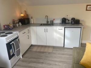 a kitchen with white cabinets and a sink and a stove at Alma’s retreat in Drogheda