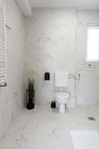 een witte badkamer met een toilet en marmeren muren bij Key Apartments in Novi Sad