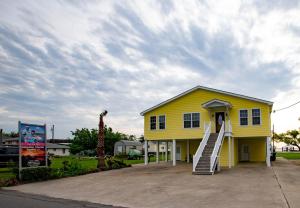 una pequeña casa amarilla con una escalera delante en Calcasieu Lodge, en Hackberry