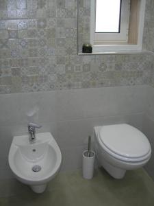 La salle de bains est pourvue de toilettes blanches et d'un lavabo. dans l'établissement Capri house, à Fasano
