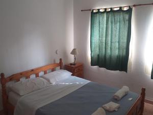 1 dormitorio con 1 cama grande y cortina verde en Aitue Departamentos en Colón