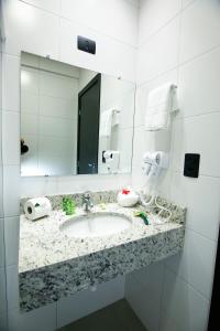 a bathroom with a sink and a mirror at NEO PARK HOTEL in Maringá