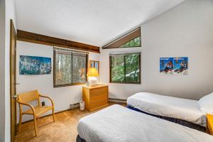 a bedroom with two beds and a chair and two windows at Dwight Road Getaway in Quechee