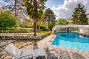 a swimming pool with two white chairs and a house at La Fauconnerie Du Roy in Montainville