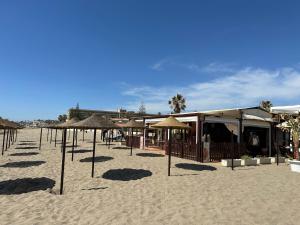 une plage avec des parasols et un bâtiment sur le sable dans l'établissement APARTAMENTOS LA CALA de MIJAS, à La Cala de Mijas