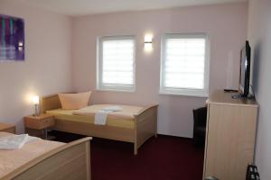 um pequeno quarto com 2 camas e uma televisão em Hotel Pension Schwerin-Haus Schreiber em Schwerin