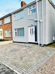 a large white house with a driveway in front of it at CozyComfy Apartment Leicester in Leicester