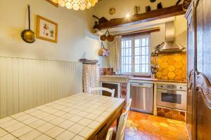 een keuken met een tafel, een fornuis en een raam bij La Fauconnerie Du Roy in Montainville