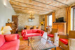 uma sala de estar com mobiliário vermelho e uma mesa em La Fauconnerie Du Roy em Montainville