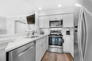 a kitchen with white cabinets and a stainless steel refrigerator at Santa Rosa Dunes 1063 in Pensacola Beach