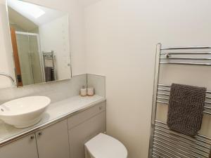 een badkamer met een wastafel, een toilet en een spiegel bij The Cwtch in Bridgend