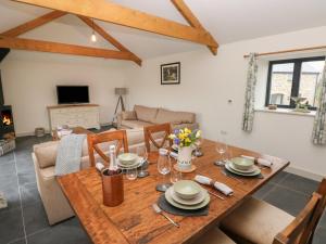 a dining room and living room with a wooden table and chairs at The Byre in Bridgend