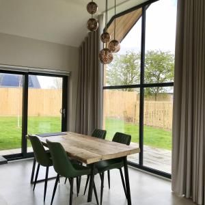 a dining room with a wooden table and green chairs at Dragonfly Cottage, Ashlin Farm Barns in Lincoln