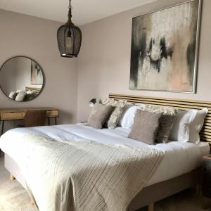 a bedroom with a large white bed with a painting on the wall at Dragonfly Cottage, Ashlin Farm Barns in Lincoln