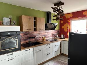 - une cuisine avec des placards blancs et une cuisinière noire dans l'établissement Wohnung Emilia, à Mörfelden-Walldorf 9 autres photos