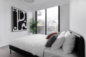 Schlafzimmer mit einem Bett mit weißer Bettwäsche und Kissen in der Unterkunft Gorgeous 3 bedrooms, Parking , New building in Tel Aviv