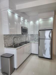 uma cozinha com armários brancos e um frigorífico de aço inoxidável em San Juan Home em San Juan