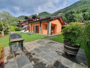 a house with a grill in front of a yard at Villa Maya in Mergozzo