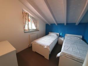 2 łóżka w pokoju z niebieskimi ścianami w obiekcie Villa Maya w mieście Mergozzo