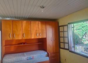 a small bedroom with wooden cabinets and a window at Chácara Sonho Meu in Pinhalzinho