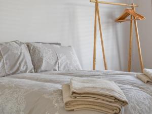 uma cama com lençóis brancos e toalhas em Cranleigh em Pakefield