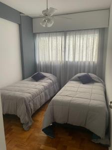 a bedroom with two beds and a ceiling fan at Departamento en peatonal Mendoza in Mendoza