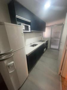 uma cozinha com um frigorífico branco e um lavatório em Departamento en peatonal Mendoza em Mendoza