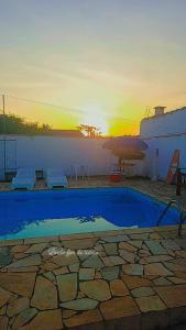a swimming pool with a sunset in the background at Pousada Litoral Norte Caragua in Caraguatatuba