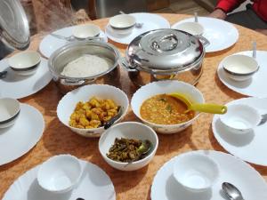einen Tisch mit weißen Tellern und Schalen mit Lebensmitteln in der Unterkunft Atithi Griha Homestay - ARITAR, SILK ROUTE, SIKKIM in Aritar